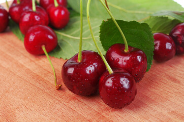 Cherry berries with leaves on a wooden table.