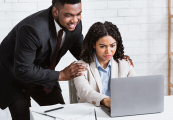 Sexual harassment at workplace. African American male boss touching his beautiful female secretary...