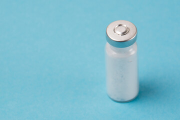 Ampoule with vaccine or medicine for covid 19 on a blue background
