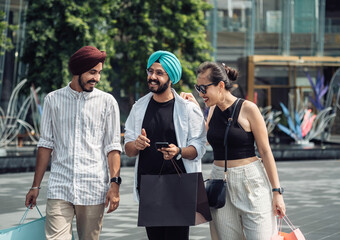 Three friends are having fun in the city while shopping and looking at smartphone together