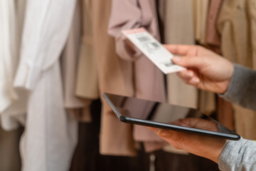 Female entrepreneur holding tablet while doing inventory in her trendy clothing shop