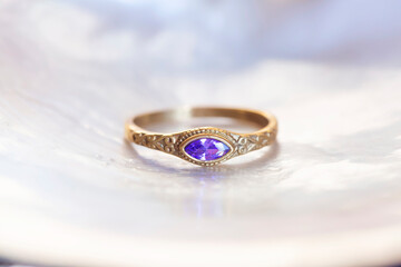Brass ring with amethyst mineral stone on white shell background