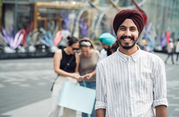 Portrait of handsome Indian man looking at camera at city street