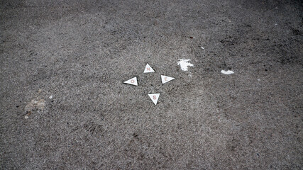 Puntos cardinales marcados en el suelo de asfalto con cuatro triángulos blancos - obrazy, fototapety, plakaty