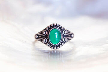 Antique silver ring with green jade mineral stone on white shell background