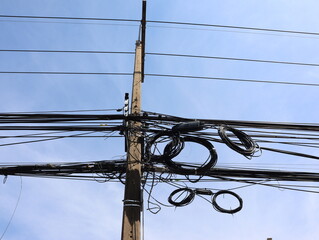 Power lines and communication cables on electric poles Bright sky background