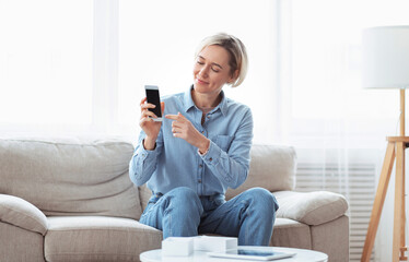 Obraz premium Popular blogger promoting new model of cellphone, filming video review of electronic device at home