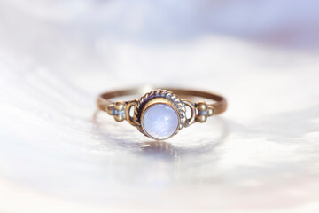Brass ring with moon stone mineral stone on white shell background