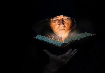 Ein älterer Mann mit Bart liest in einem mystischen Buch