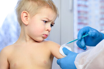 Doctor injecting vaccination in arm of a little boy. Coronavirus vaccination. Doctor vaccinating child. Little boy getting flu shot. Pediatrician giving injection.