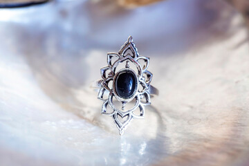 Antique silver ring with black onyx mineral stone on white shell background