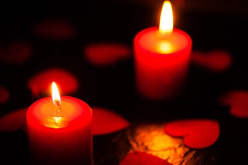 Two red burning candles. Candles with hearts. The background for the greeting card. A greeting card for Valentine's Day. February 14 is valentine's day. Used as a background or texture, soft focus