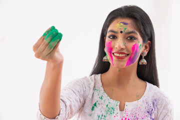 A HAPPY YOUNG WOMAN WITH GULAL IN HAND WHILE CELEBRATING HOLI	
