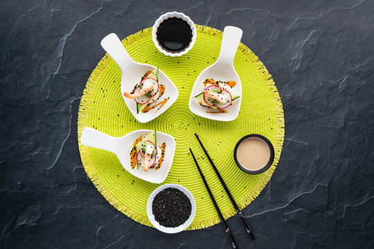 Top Down View Of Small Dishes Of Homemade Deconstructed Sushi On A Bright Green Mat.