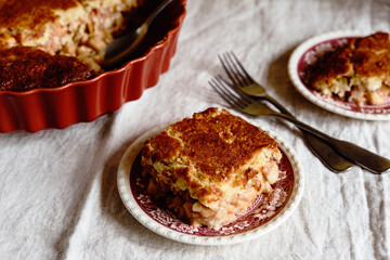 Apple and Cheese Cobbler Crisp. Cobbler or Crumble dessert with apples in ceramic baking form on beige linen table. Selective focus