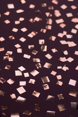 Shiny pink confetti on burgundy background. Modern abstract background and texture.