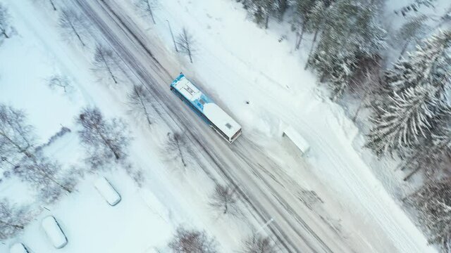The city bus is moving on the street in winter.