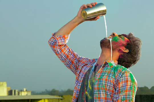 A YOUNG MAN CHEERFULLY DRINKING BHANG DURING HOLI CELEBRATIONS	