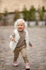 Curly toddler with blond hair having fun on a walk on a summer day