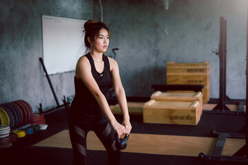 Asian woman in exercise clothes focus on lifting dumbbell in the gym.