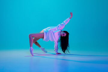 Dance. Young and graceful ballet dancer isolated on blue studio background in neon light. Art,...