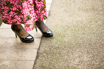 dettaglio di scarpe nere indossate da una ragazza con un abito a fiori