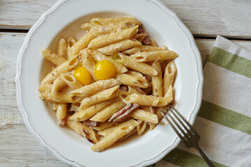 Spaghetti Carbonara, pasta with bacon, egg, hard parmesan cheese and cream sauce. Traditional italian Pasta alla carbonara on white, top view, copy space.