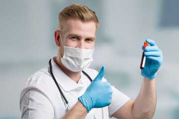 doctor with medical face mask and blood probe shows thumbs up