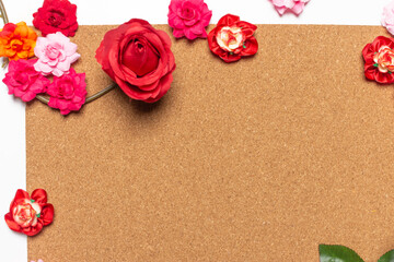 Frame made of rose flowers on cork board  background. Top view with copy space.