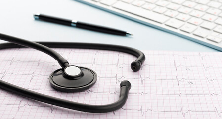 Stethoscope on cardiogram with pen and keyboard on blue background. Cardiology concept. Panoramic web banner.