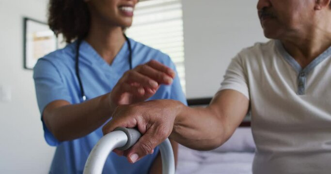 Close up of senior mixed race man with female doctor home visiting holding hands