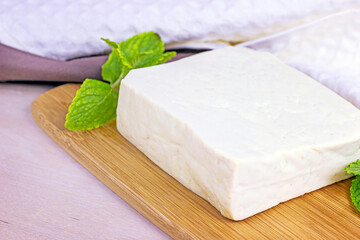 Raw organic vegetarian tofu slices with fresh mint on wooden background.