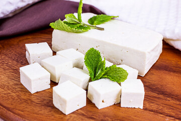 Raw organic vegetarian tofu slices with fresh mint on wooden background.