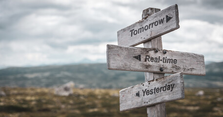 tomorrow real time yesterday text engraved on wooden signpost outdoors in nature. Panorama format. - obrazy, fototapety, plakaty