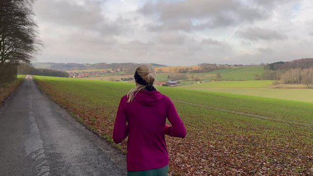 Young Athletic Woman Running On rural Trail. Pov Follow rear Cam. Sunny and cloudy day outdoors in autumn.