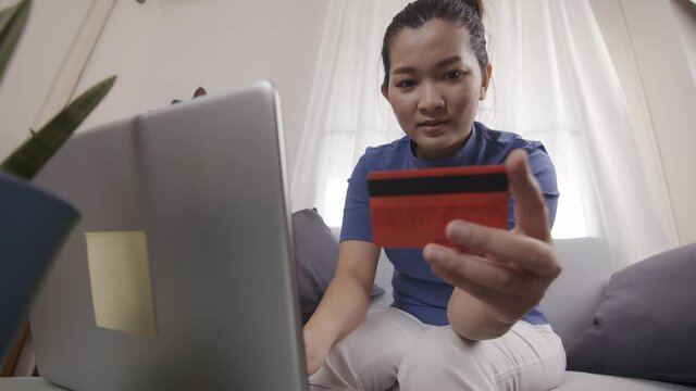 New normal Asian women are using cards to pay for online shopping on a laptop