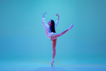Dreamful. Young and graceful ballet dancer isolated on blue studio background in neon light. Art,...