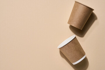 Renewable individual objects for home use, bamboo or paper straws, disposable cups and wooden coffee stirrers on beige with shade from the leaves on beach. Zero waste. Pollution environment. Top view.