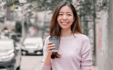 Woman drinking coffee while walking beside street