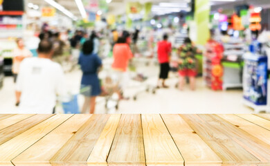 Wooden board empty table on front with blurry many crowd anomynous waiting for payment at cashier.