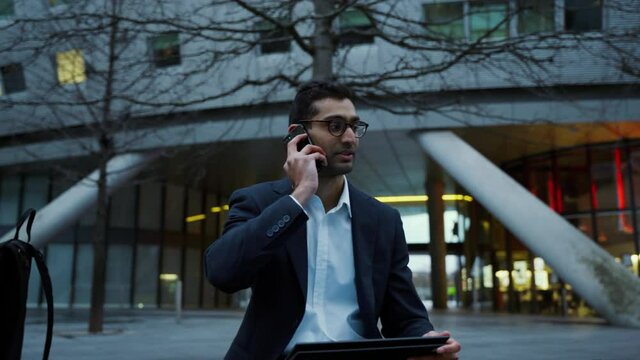 Mixed race businessman chatting to colleagues on smartphone sitting outside in the city, getting work finished