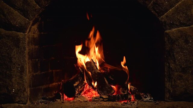 Fire is burning in the fireplace. Warmth and home comfort. Flame of a country house. Firewood is burning in the hearth. Detailed fire background. 4K