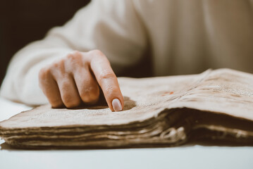 Woman reading ancient book - Bible. Concentrated attentively follows finger on paper page in library. Old archival manuscripts. History concept.