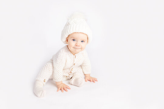 Baby Crawls In A Warm Suit And Hat On A White Isolated Background, Space For Text