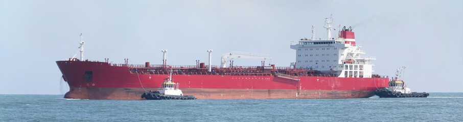 Obraz premium oil tanker being pushed by tugboats