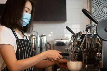 Asian barista woman wearing face masks To prevent contagious diseases And brewing coffee in the coffee shop. The concept of prevention from COVID 19