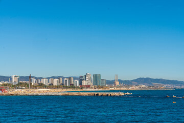 Fototapeta premium BARCELONA, SPAIN, FEBRUARY 3, 2021: Barcelona coast a sunny winter day. During the covid-19 pandemic. View from inside the water. In the background we can see the new modernist buildings on the coast.