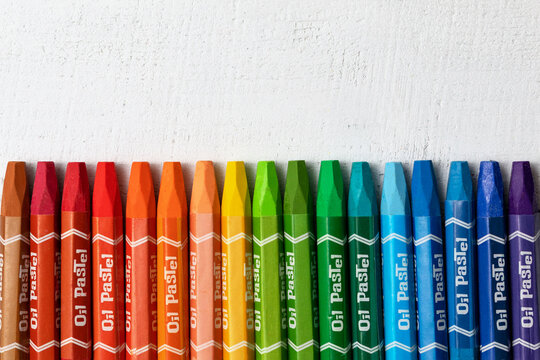 colored crayons with the inscription "oil pastel" for drawing on a white wooden background. a set for a young artist. the concept of creativity. top view.