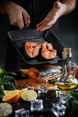 Fresh salmon steaks in a frying pan. The chef uses a knife to cut the salmon into steaks.