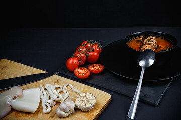 Soup with seafood and vegetables. Still life on a dark background.